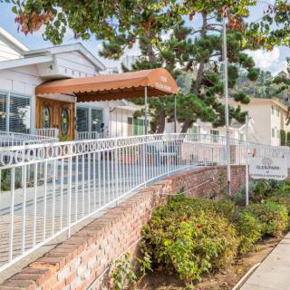 A building entrance with a ramp, surrounded by landscaping and trees.