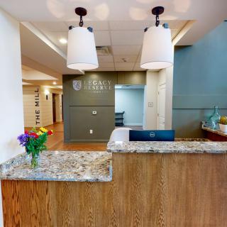 A welcoming reception area with a granite desk, decorative lighting, and a vase of flowers.