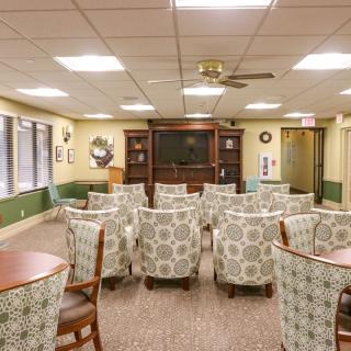 A cozy seating area with patterned chairs arranged facing a television in a well-lit room.