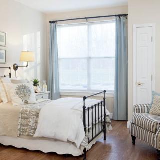 A cozy bedroom with a metal bed frame, soft lighting, and neutral color tones.