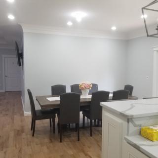 A modern dining room with a large table and chairs, featuring stylish lighting and hardwood floors.