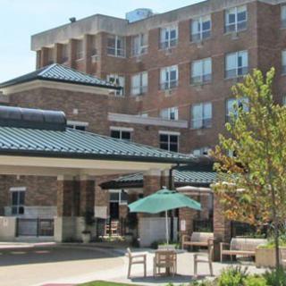 A brick healthcare facility with outdoor seating and landscaping.