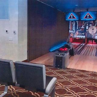 An indoor bowling alley with a seating area and carpeted floor.
