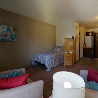 A cozy bedroom featuring a bed, seating area with colorful cushions, and an inviting ambiance.