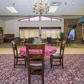 A cozy dining area with a round table and chairs, adorned with a patterned carpet and lit by a chandelier.