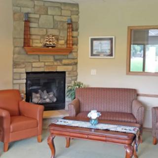 A cozy living room featuring a stone fireplace, armchair, sofa, and coffee table with decorative items.