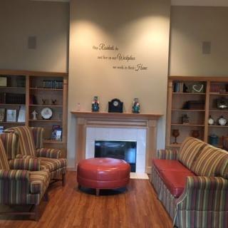 A cozy living room with a fireplace, surrounded by bookshelves and comfortable seating.