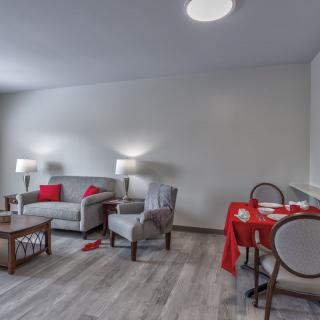 A modern living and dining area featuring a comfortable sofa and chairs, with red accents adding a pop of color.
