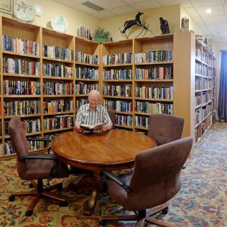 A person reading a book at a round table in a cozy library.