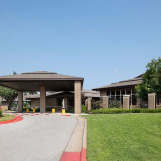 A modern building with a covered entrance and landscaped surroundings.