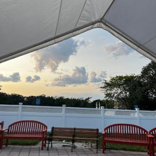 A serene view of the sunset from under a canopy, featuring red benches in a park setting.