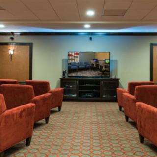 A cozy home theater with rows of red chairs facing a large television.