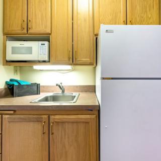 A compact kitchen area with a refrigerator, microwave, sink, and wooden cabinets.
