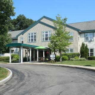 A residential building with a covered entrance, surrounded by trees and landscaping.
