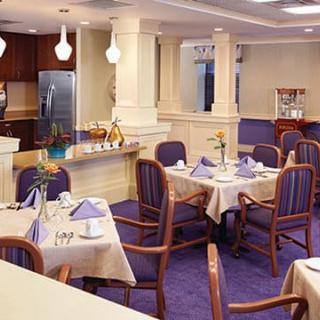 A dining area with elegantly set tables and purple carpeting.