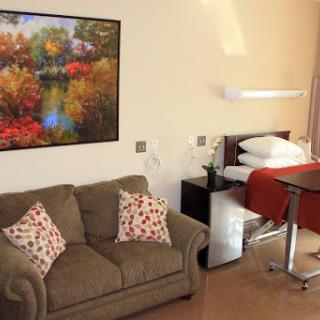 A cozy living space featuring a comfortable sofa, a neatly made bed, and a vibrant painting on the wall.