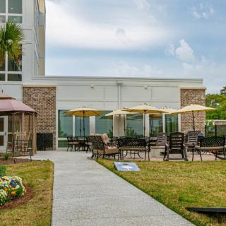 A modern building with an outdoor patio area featuring chairs and umbrellas, ideal for relaxation.