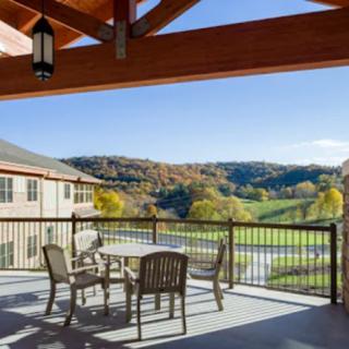 A spacious balcony with outdoor seating overlooks a scenic landscape.