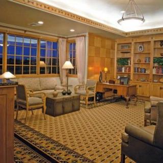 A cozy living room with a wooden bookcase, comfortable sofas, and soft lighting.