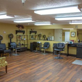 An empty hair salon with multiple styling stations and wooden flooring.