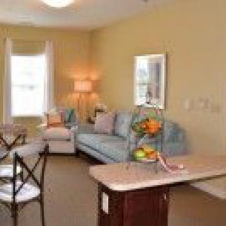 A cozy living room with a sofa, lamp, and a table adorned with fruit.