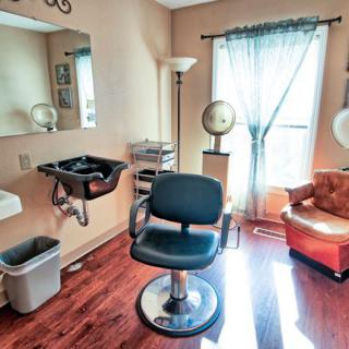 A cozy hair salon interior featuring a styling chair, sink, and vintage dryer.