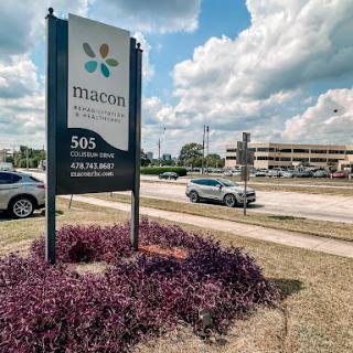 Sign showing the location and name of a business with a landscaped entrance.