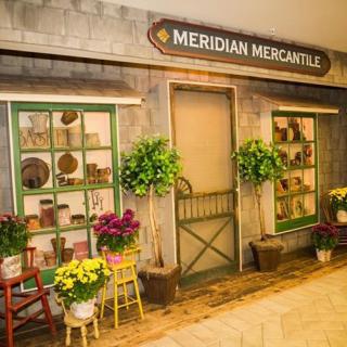 A charming vintage storefront named Meridian Mercantile, adorned with vibrant flowers and plants.