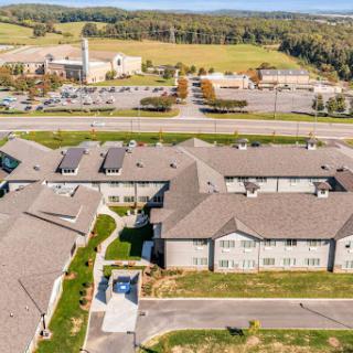 Aerial view of a residential complex surrounded by open fields and a parking area.