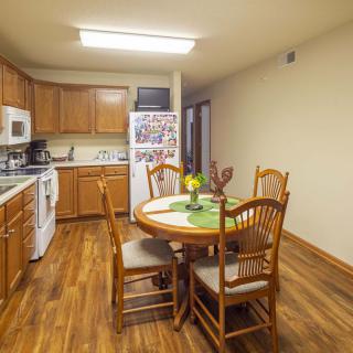 A cozy kitchen with a wooden dining table and chairs next to modern appliances.