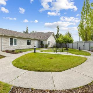A spacious backyard with a well-maintained lawn and winding pathways surrounded by a wooden fence.