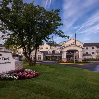 A picturesque view of a residential building with a well-maintained garden and entrance sign against a clear sky.