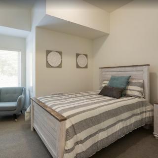 A cozy bedroom with a striped bedding set and neutral decor.