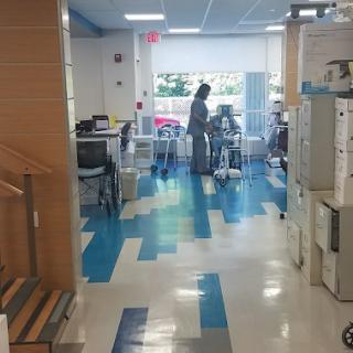 A modern office space with blue and white flooring, featuring people working in the background.