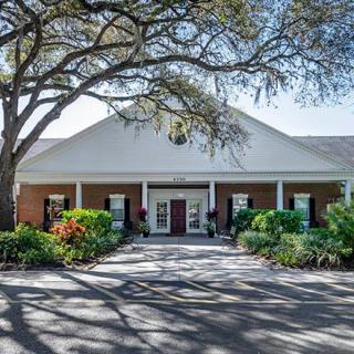A large building with a brick facade, surrounded by trees and well-maintained landscaping.