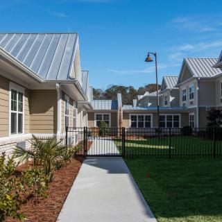 A modern residential housing community with a landscaped pathway and metal fencing.
