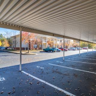 A view of a covered parking area with colorful autumn trees and parked cars.