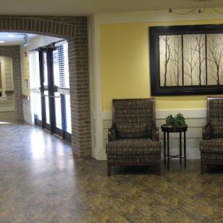 A cozy seating area in a well-lit lobby, featuring patterned chairs and decorative wall art.
