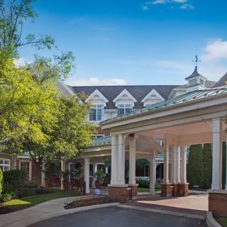 A welcoming entrance to a large building with elegant architecture and well-maintained landscaping.