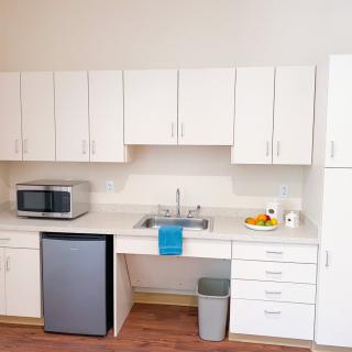 Minimalist kitchen setup with white cabinets and a small fridge.