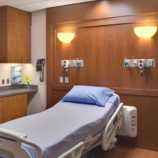 A clean and modern hospital room with a neatly made bed and medical equipment.