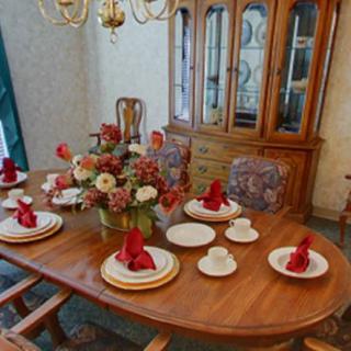 A formal dining room setup with a flower centerpiece and red napkin arrangements on the table.
