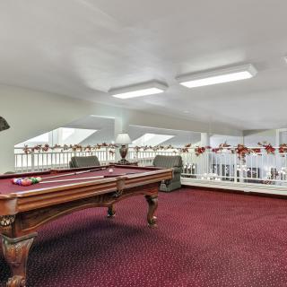 A spacious loft area with a billiards table and red carpet.