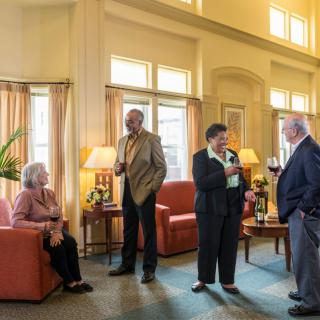 A group of people socializing in a warmly lit living room.