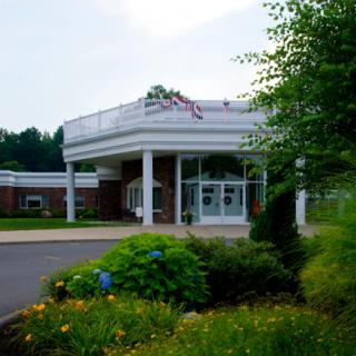 A welcoming entrance to a healthcare facility surrounded by vibrant greenery and flowers.