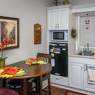 A cozy kitchen with a small dining area featuring a wooden table and chairs, complete with festive decor and modern appliances.