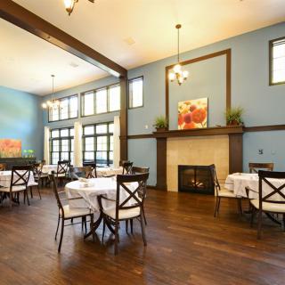 A spacious dining area with blue walls, elegantly set tables, and a cozy fireplace.