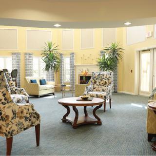 A cozy and well-decorated living room with floral chairs, a coffee table, and potted plants.