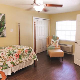 A cozy bedroom with a floral bedspread, armchair, and closet.