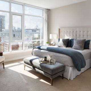A modern and luxurious bedroom with large windows offering a stunning city view.